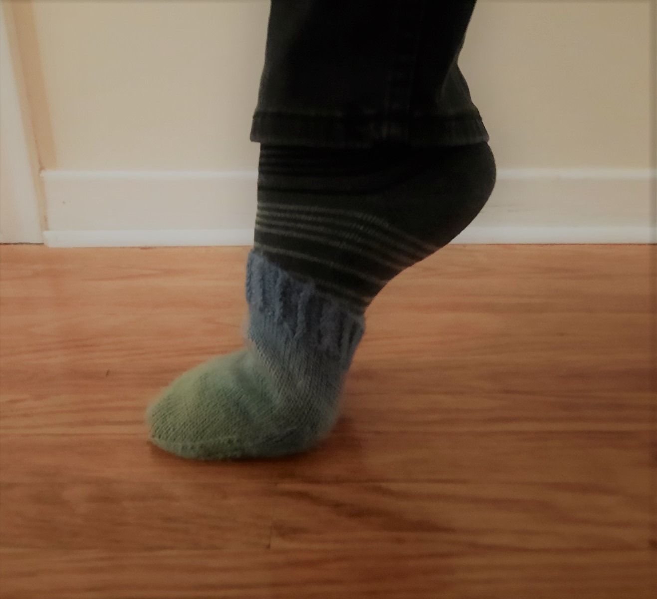 Toe A single foot wearing a grey striped sock, and a bright wool toe cover over that.